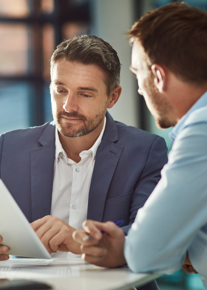Two guys sitting down for a discussion. The one on the left is holding a tablet while the one on the right speaks to him. Two guys sitting down for a discussion. The one on the left is holding a tablet while the one on the right speaks to him.